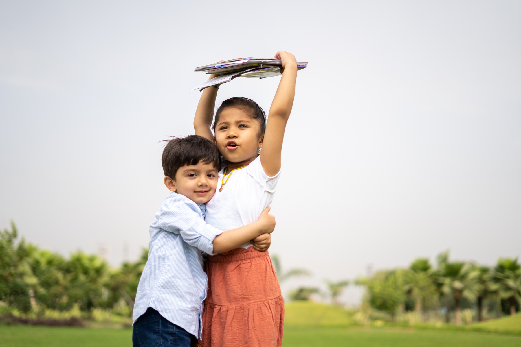Boy Hugging a Girl Holding Books Outdoors